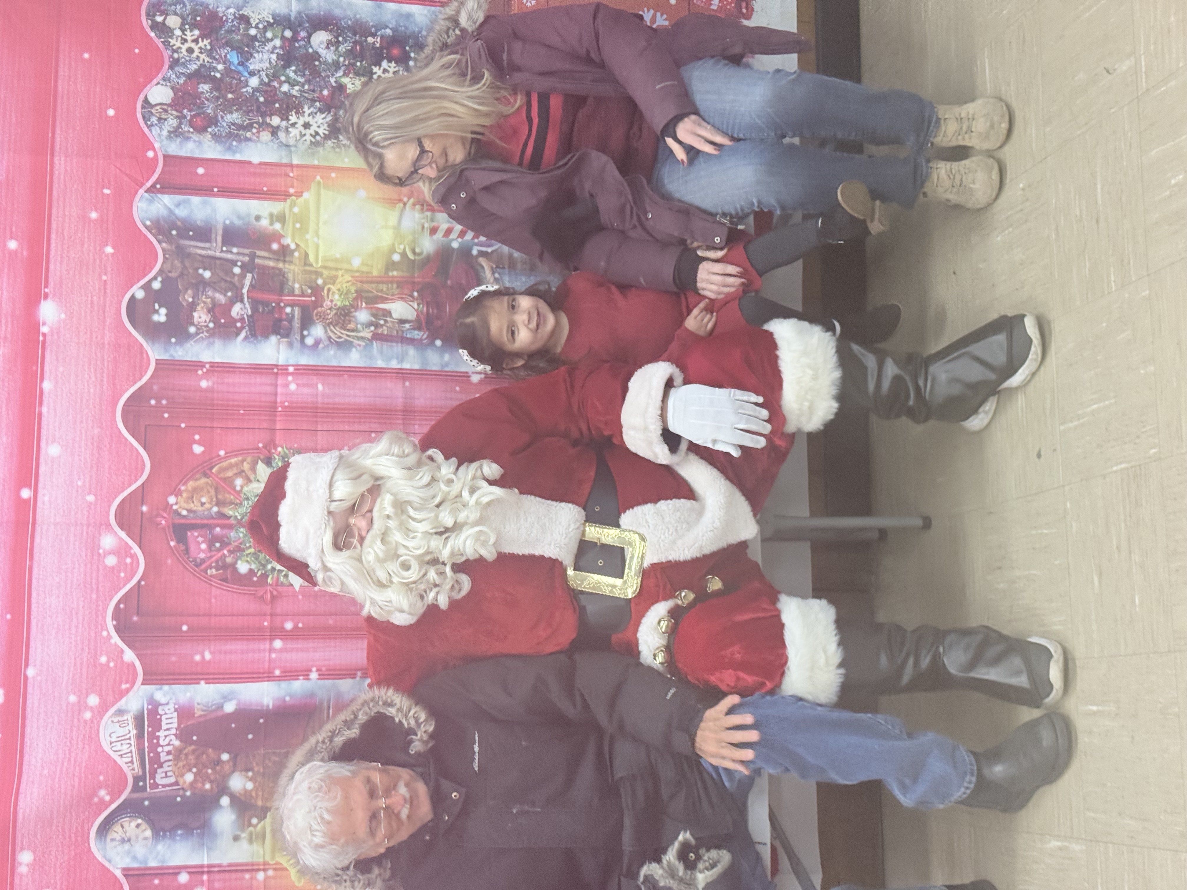 A family poses with Santa at a Christmas backdrop.